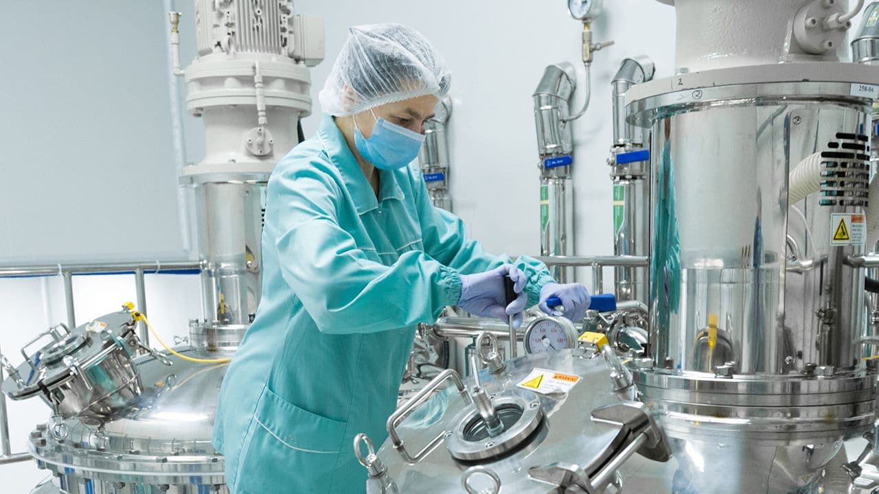 Ivan Traimak/Stock.Adobe.com – image of pharmaceutical personnel working with bioreactor